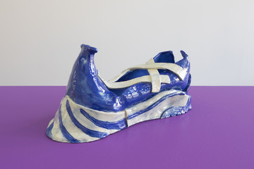 Michael Portnoy, The 16 Psyche Gluttons (2020)
 The asteroid 16 Psyche is said to have enough gold and platinum to make everyone on earth a billionaire. But why wait in poverty until we reach the asteroid belt to mine it? These shoes send out gold guzzling NanoWhales© on the quantum ocean to gulp down gold ions from 16 Psyche and bring them back to the wearer. In only five years of daily wear, the shoe will become fully encrusted with gold and must then be submitted to a governing body in Luxembourg which redistributes the wealth fairly around the world.  
Ceramic 
30 x 12 cm x 14 cm - © Photo: Robert Glas, Paris Internationale